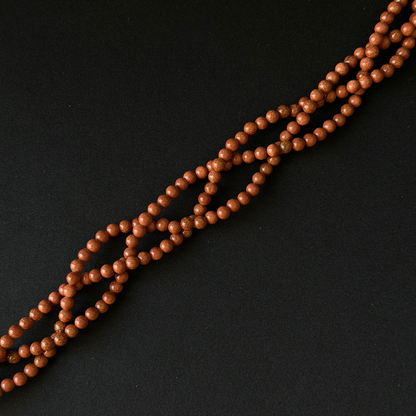 A strand of small, polished brown wooden beads arranged diagonally on a dark black background.