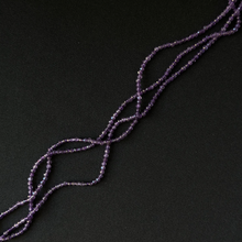Purple Amethyst beaded strands arranged diagonally on a dark black background.