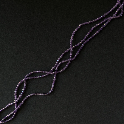 Purple Amethyst beaded strands arranged diagonally on a dark black background.