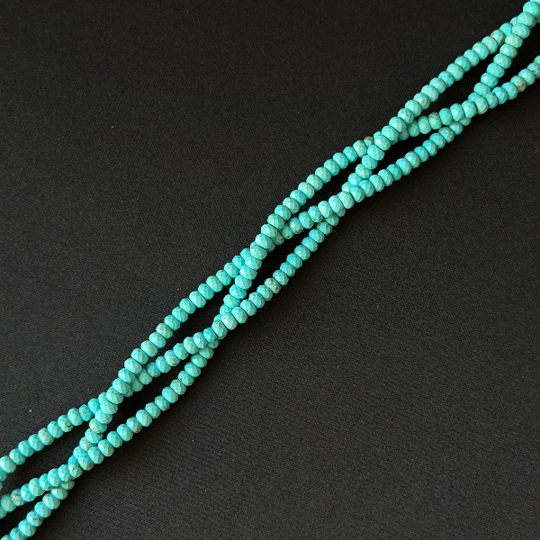 Turquoise beaded strands arranged diagonally on a dark textured background.