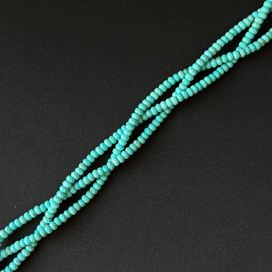 Turquoise beaded strands arranged diagonally on a dark textured background.