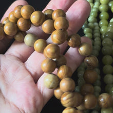 brown wood grain jasper beads in a close up video with beads in a persons hand. smooth round beads