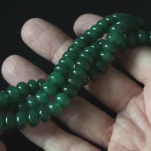 close up video of dark green dyed jade rondelle beads in hand