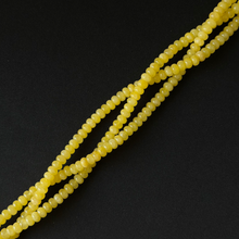 Multiple strands of small, smooth yellow beads arranged diagonally on a solid black background.